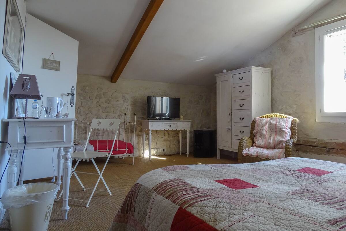 A bedroom with a bed, a television, a wardrobe, a desk, and a chair.