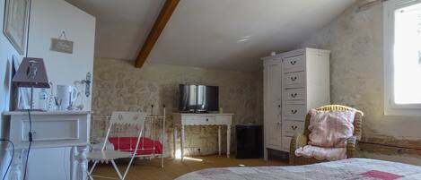 Ein Schlafzimmer mit einem Bett, einem Fernseher, einem Kleiderschrank, einem Schreibtisch und einem Stuhl.