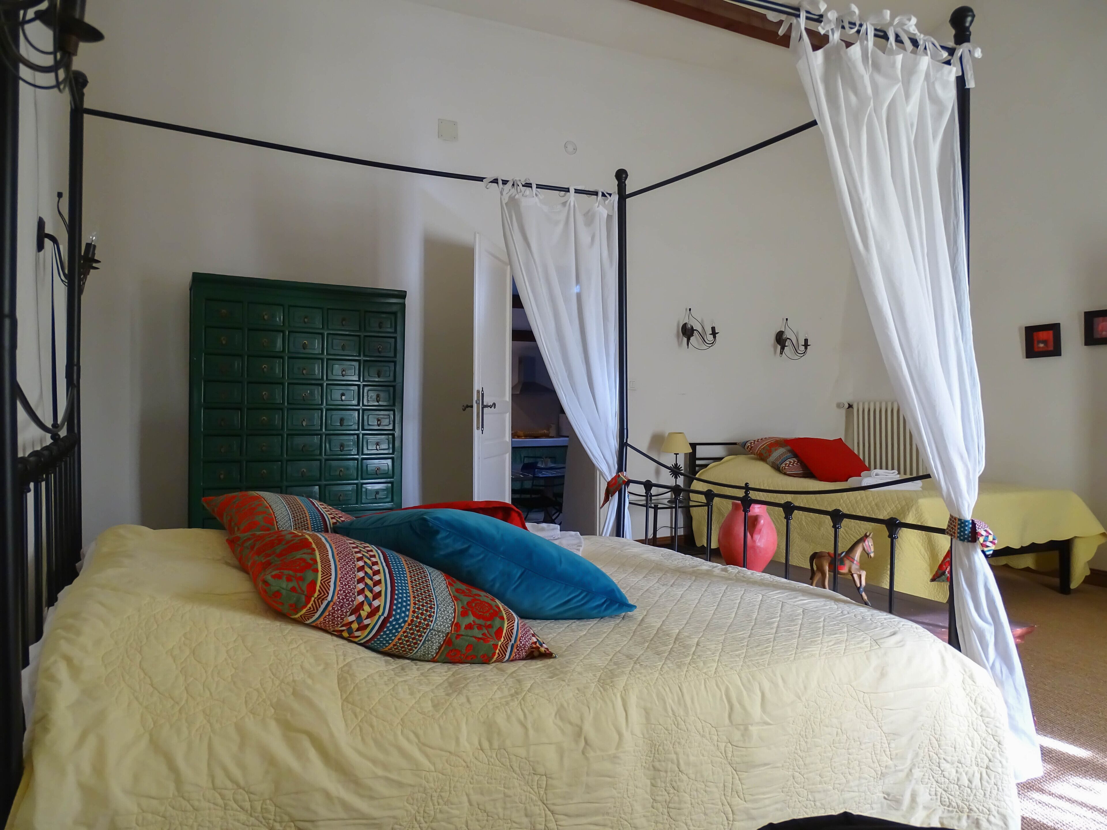 Uma cama com dossel, um aparador verde e um edredom amarelo.