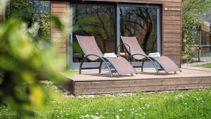 Un área lounge moderna al aire libre con dos sillones reclinables y una pequeña mesa, probablemente parte de un spa o centro de bienestar.