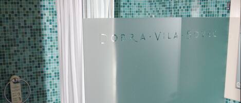 Un baño con cortina de ducha, toallero y lavamanos con espejo.