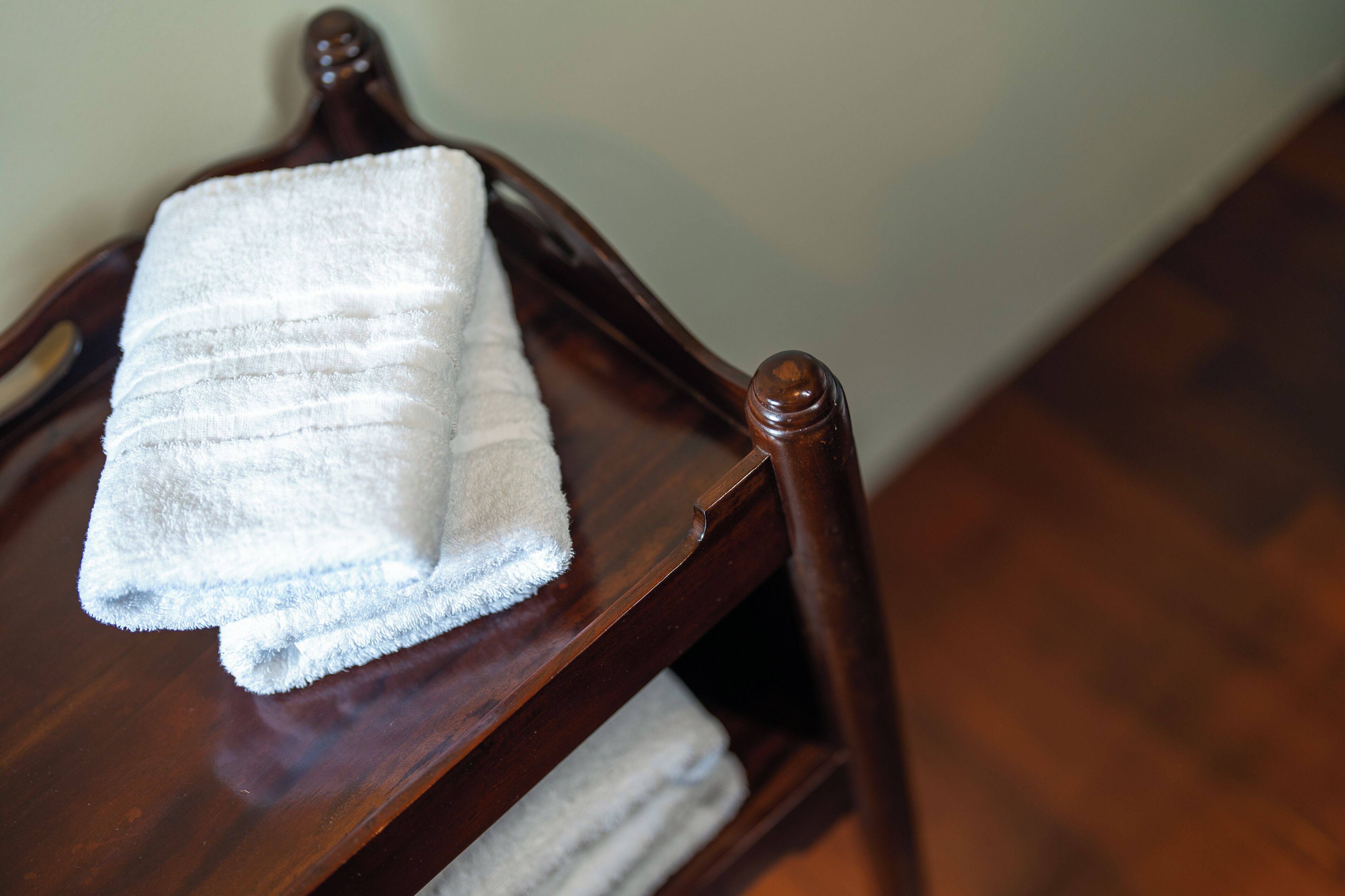 A wooden chair with a folded white towel on it.