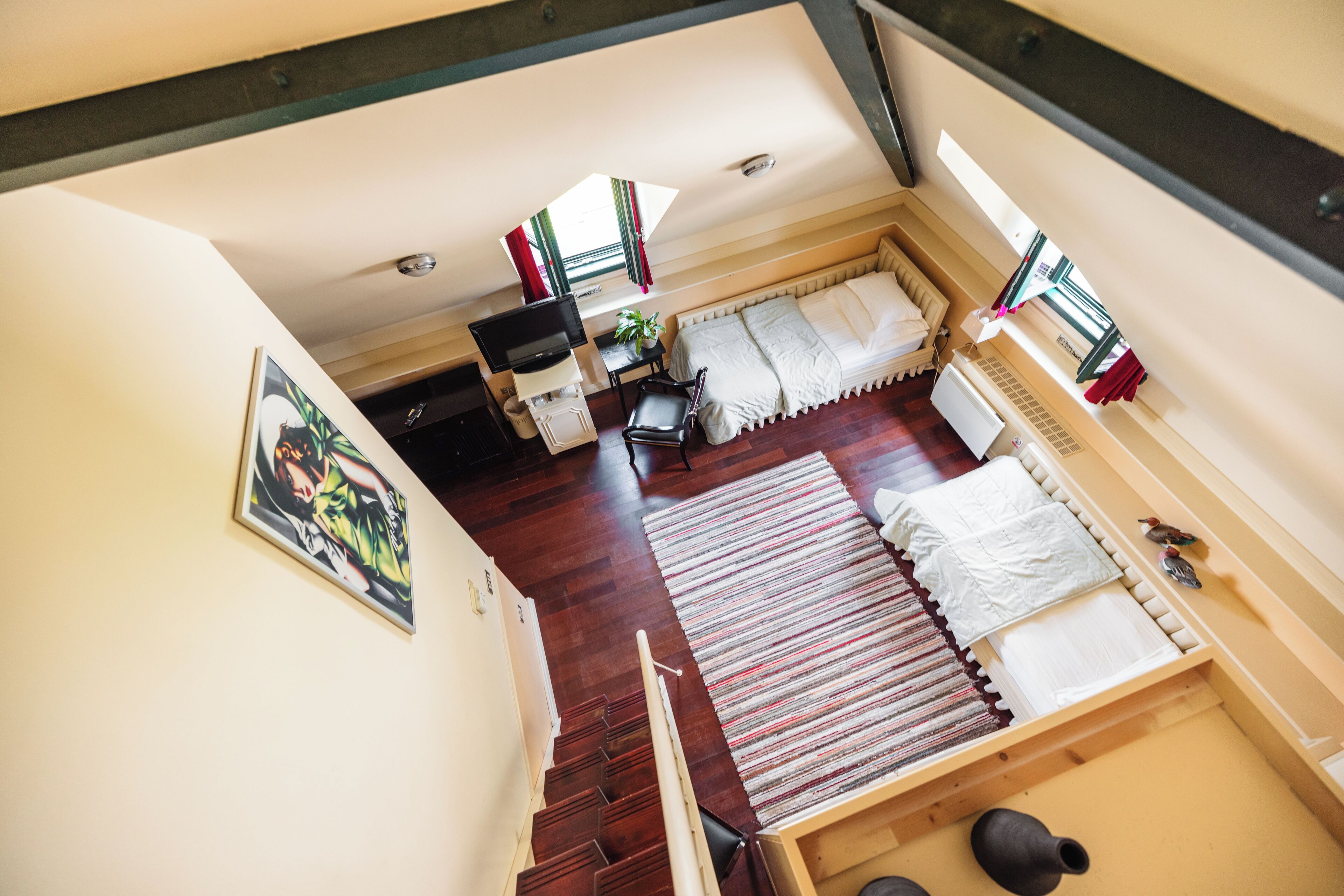Ein Zimmer mit einem Bett, einem Schreibtisch, einem Stuhl, einer Pflanze und einem Fenster.