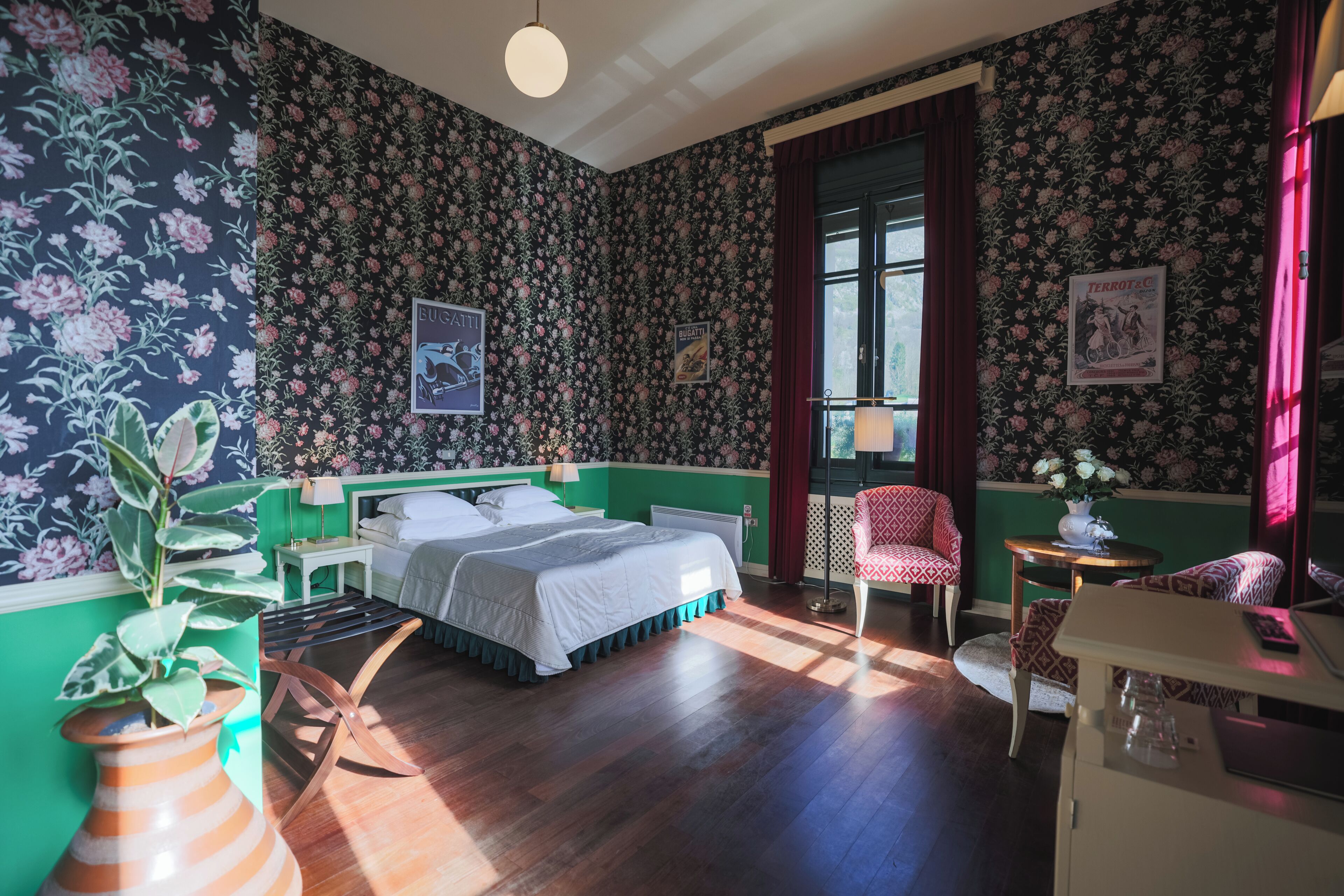 A room with a bed, a chair, a table, and a window.
