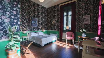 A room with a bed, a chair, a table, and a window.