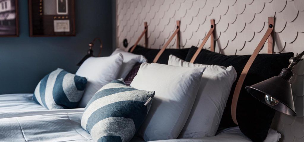 A bed with striped pillows and a headboard with a scalloped design.