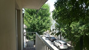 Ein Balkon mit Blick auf geparkte Autos und Bäume.
