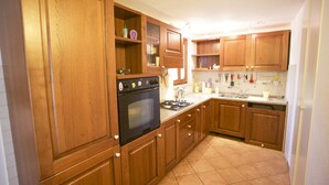 Une cuisine avec des meubles de rangement en bois, une cuisinière et un évier.
