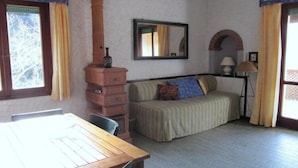 Una habitación con una mesa de madera, un sofá, una chimenea, un espejo y una lámpara.