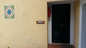 Entrada de un edificio con una puerta, un extintor y un cartel que dice "EL PRADO".