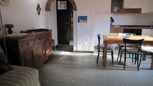 Una cocina compacta con zona de comedor, que incluye una mesa y sillas de madera, horno empotrado y refrigerador.