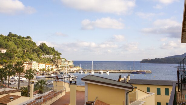 A coastal town with buildings, a marina, and boats. - Appartamento Quadri Azzurro (Porto Azzurro)