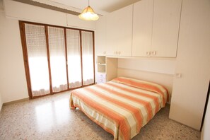 A bedroom with a bed, a wardrobe, and a window with curtains.