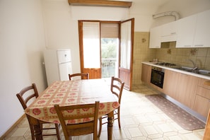 Une petite cuisine équipée d’une table à manger, de chaises, d’un réfrigérateur, d’une cuisinière et de placards.