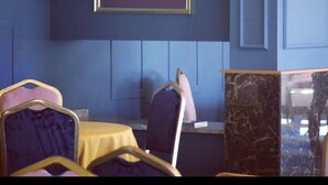 A room with a dark blue wall, a framed picture, and a bed with a yellow cover. - Grand Urfa Hotel (Sanliurfa)