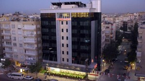 A modern building with a glass facade, multiple floors, and a prominent entrance area with a sign. - Grand Urfa Hotel (Sanliurfa)