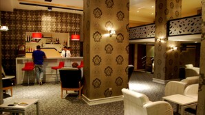 A hotel lobby with a bar area, seating arrangements, and patterned wallpaper. - Grand Urfa Hotel (Sanliurfa)