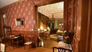 A traditional dining room with wooden furniture, a staircase, and floral wallpaper. - 1890 Williams House Inn (Hot Springs)