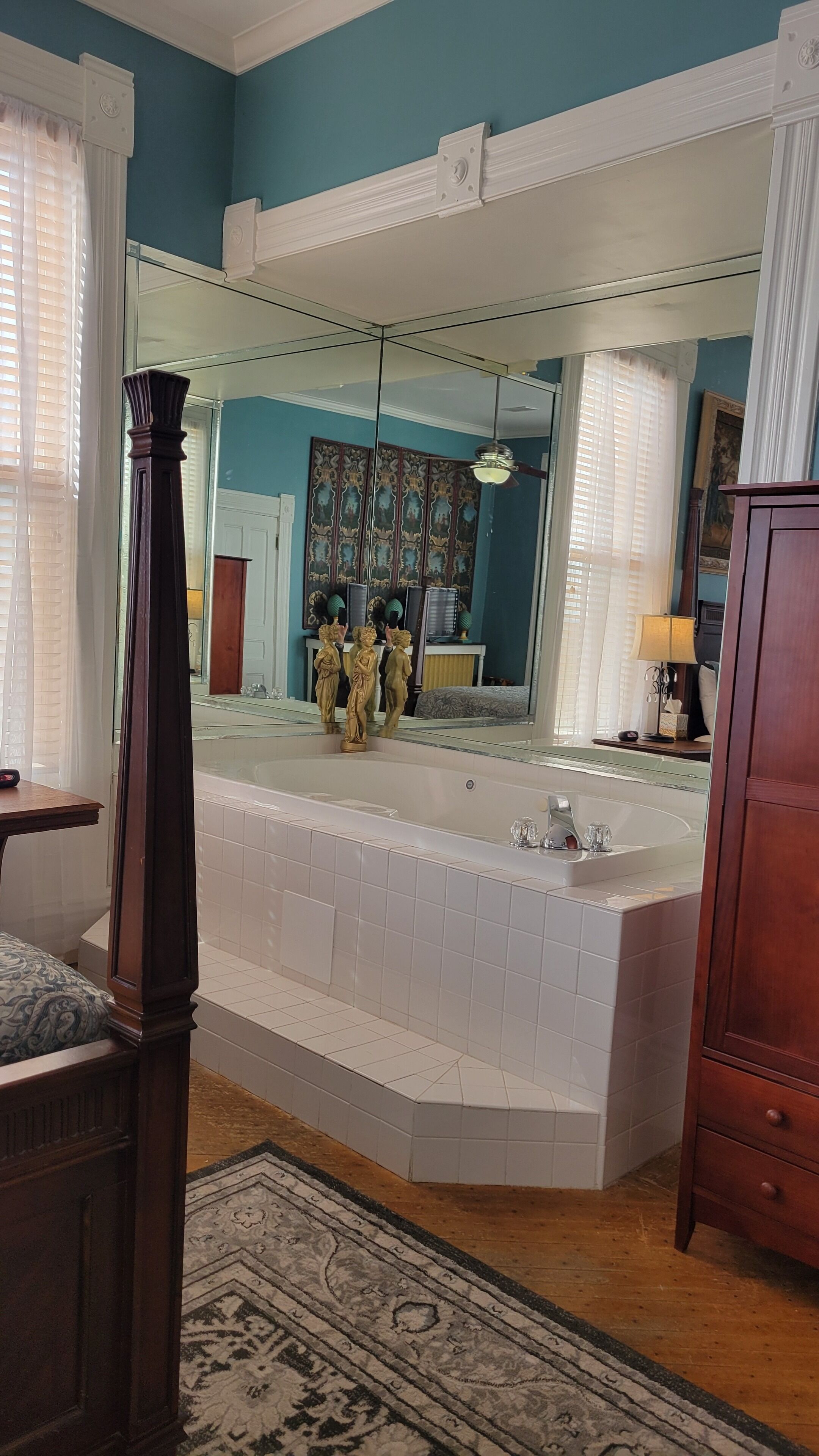 Un baño con una bañera grande, un espejo y suelo de madera.