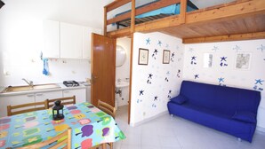 A room with a bunk bed, a dining table with a colorful tablecloth, a blue sofa, and star-themed wall decorations. - Appartamenti Il Marino (Marciana)