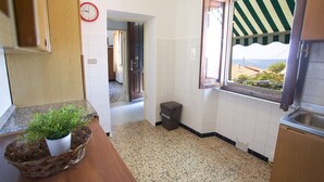 A kitchen with a wooden countertop, a potted plant, a trash bin, and a window with a view. - Appartamenti Il Marino (Marciana)