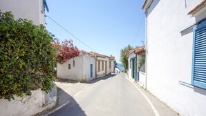 A narrow street with white buildings, blue shutters, and a clear sky. - Appartamenti Il Marino (Marciana)