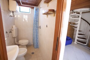 A compact bathroom with a toilet, sink, and shower. - Appartamenti Il Marino (Marciana)