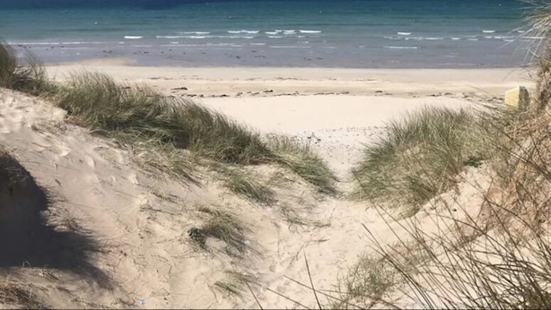 A beach with clear blue water and sandy shores.