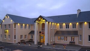 A hotel with a central entrance, multiple windows, and outdoor seating areas.