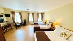A hotel room with two beds, a desk, a chair, and a TV.