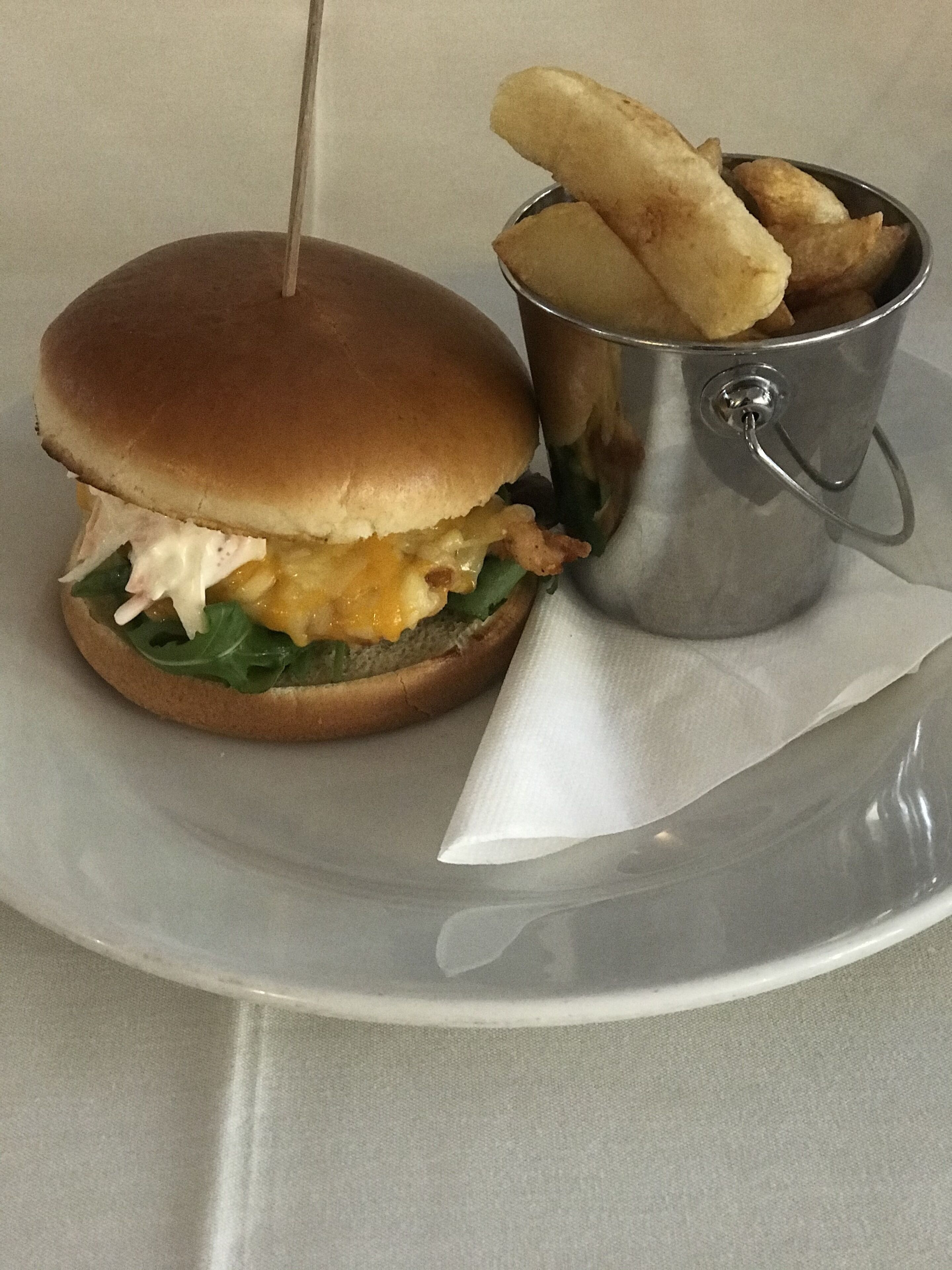 Un hamburger accompagné d’une portion de frites, le tout servi sur une assiette.