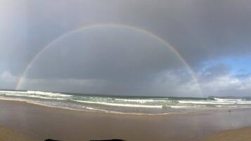 A beach with a rainbow over the ocean.