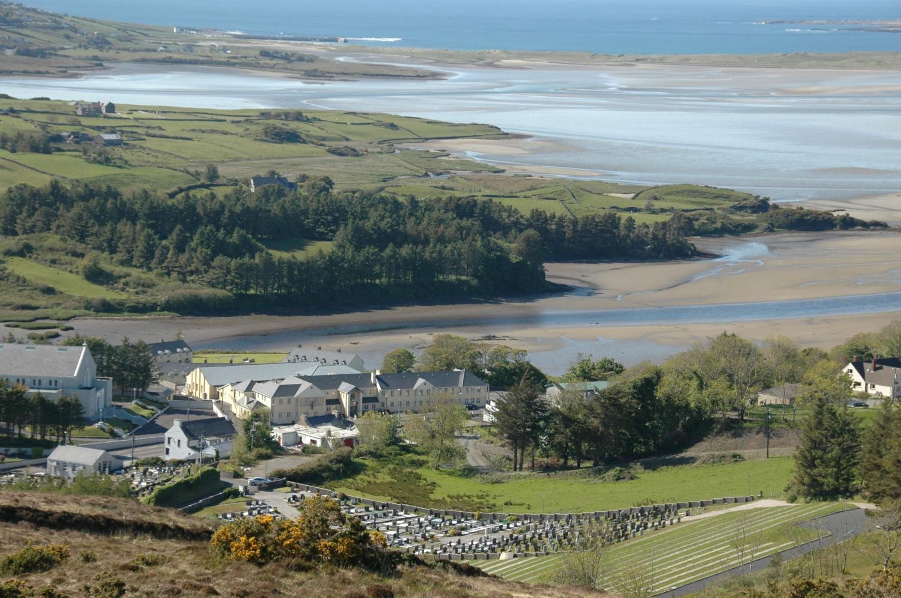 A coastal town with a cemetery, houses, and a large body of water.