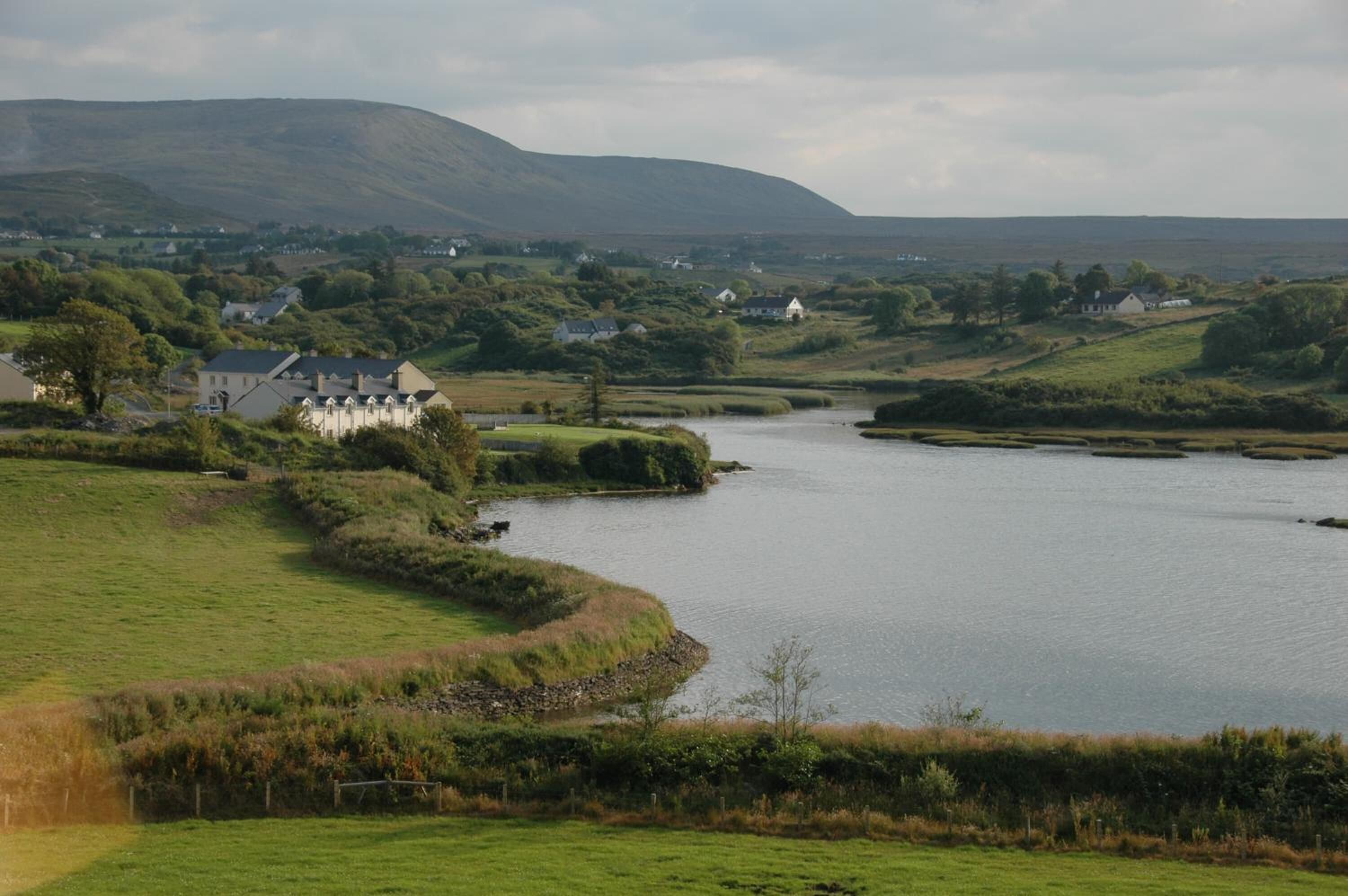 Une vue sur la rivière, avec des maisons et une colline en arrière-plan.