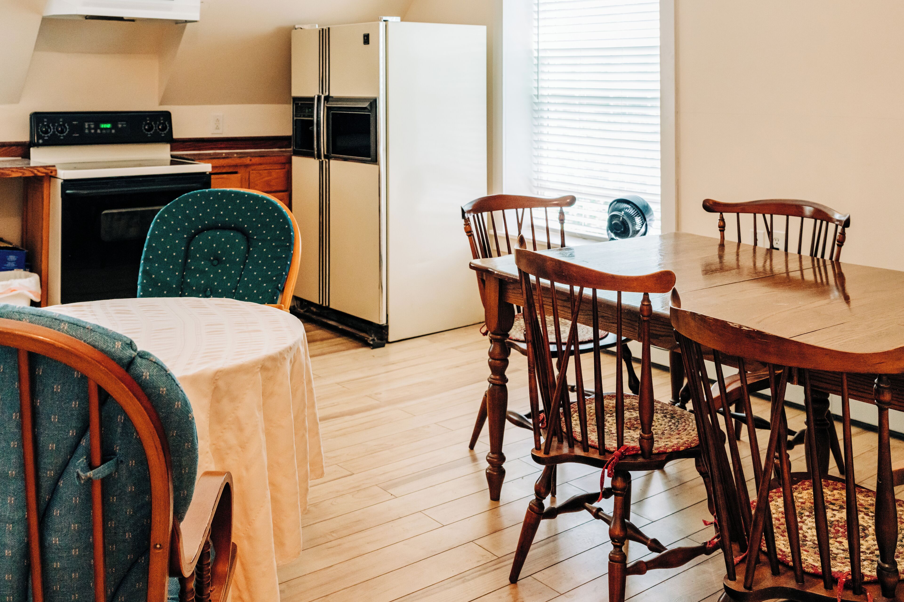 Una cocina con armarios de madera, un refrigerador blanco y una mesa de comedor con cuatro sillas.