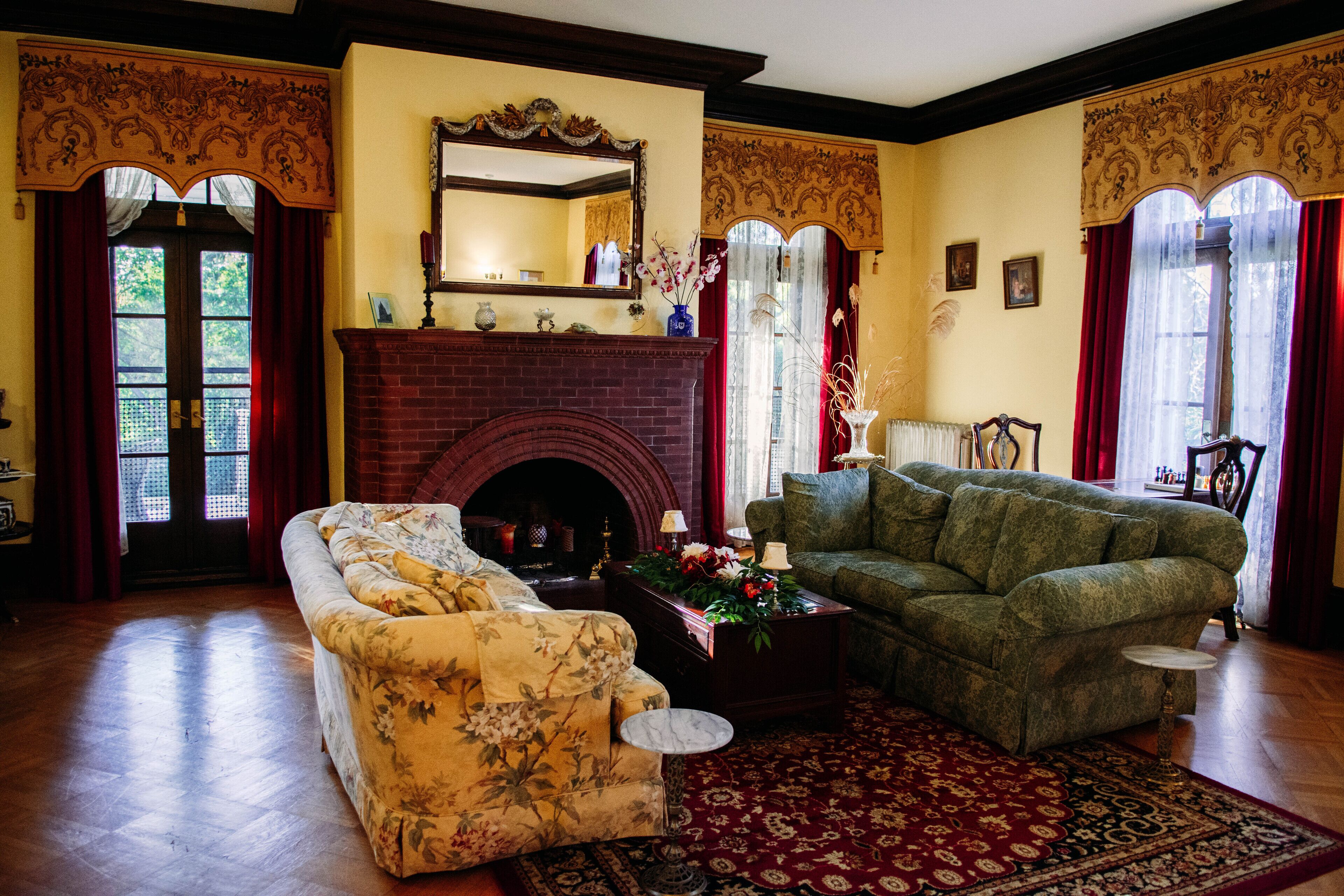 Un salon traditionnel avec une cheminée, deux canapés et un tapis à motifs.