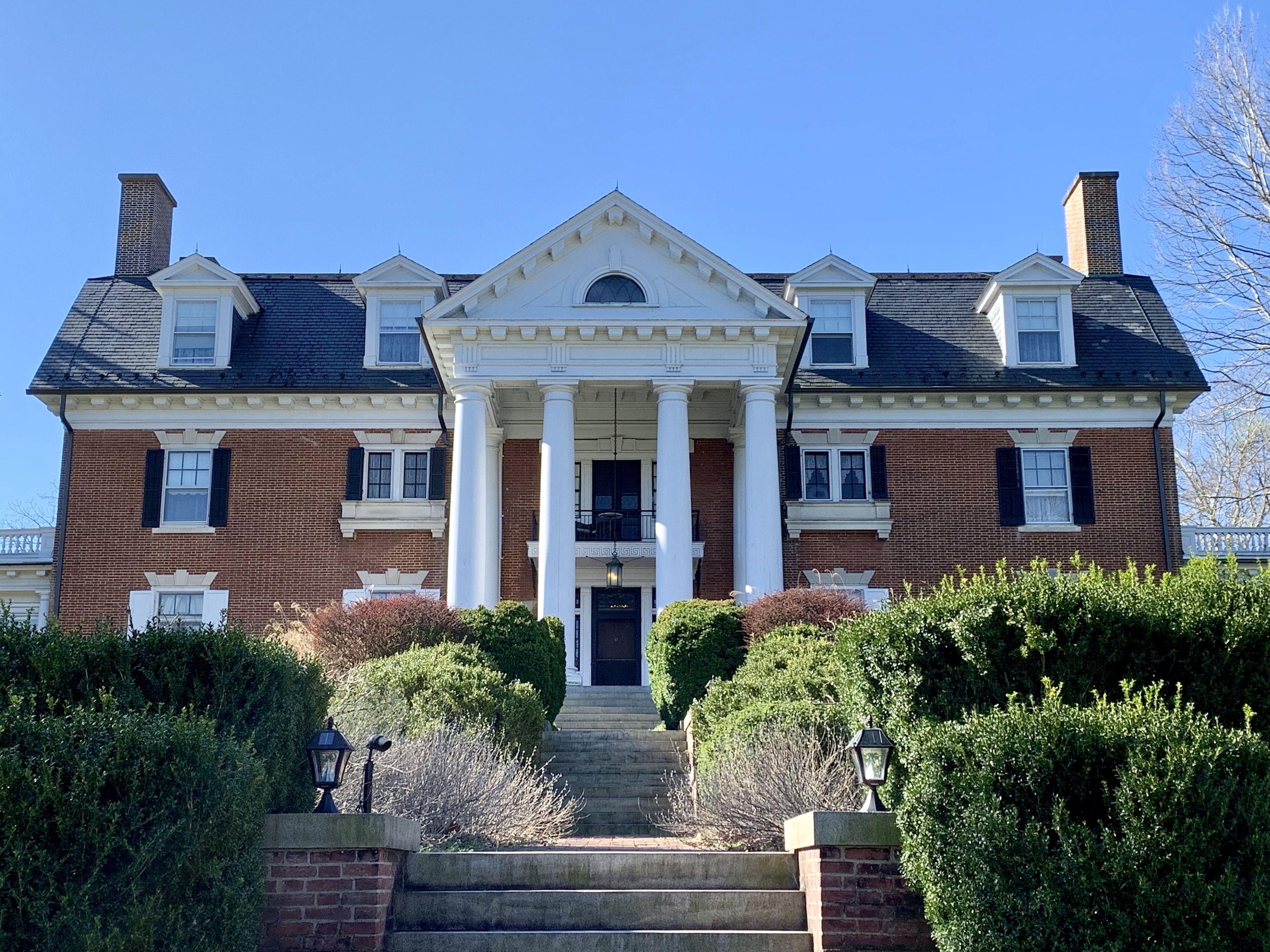 Un grand bâtiment imposant, doté d’une façade symétrique, d’une entrée centrale flanquée de colonnes et d’une façade en briques.