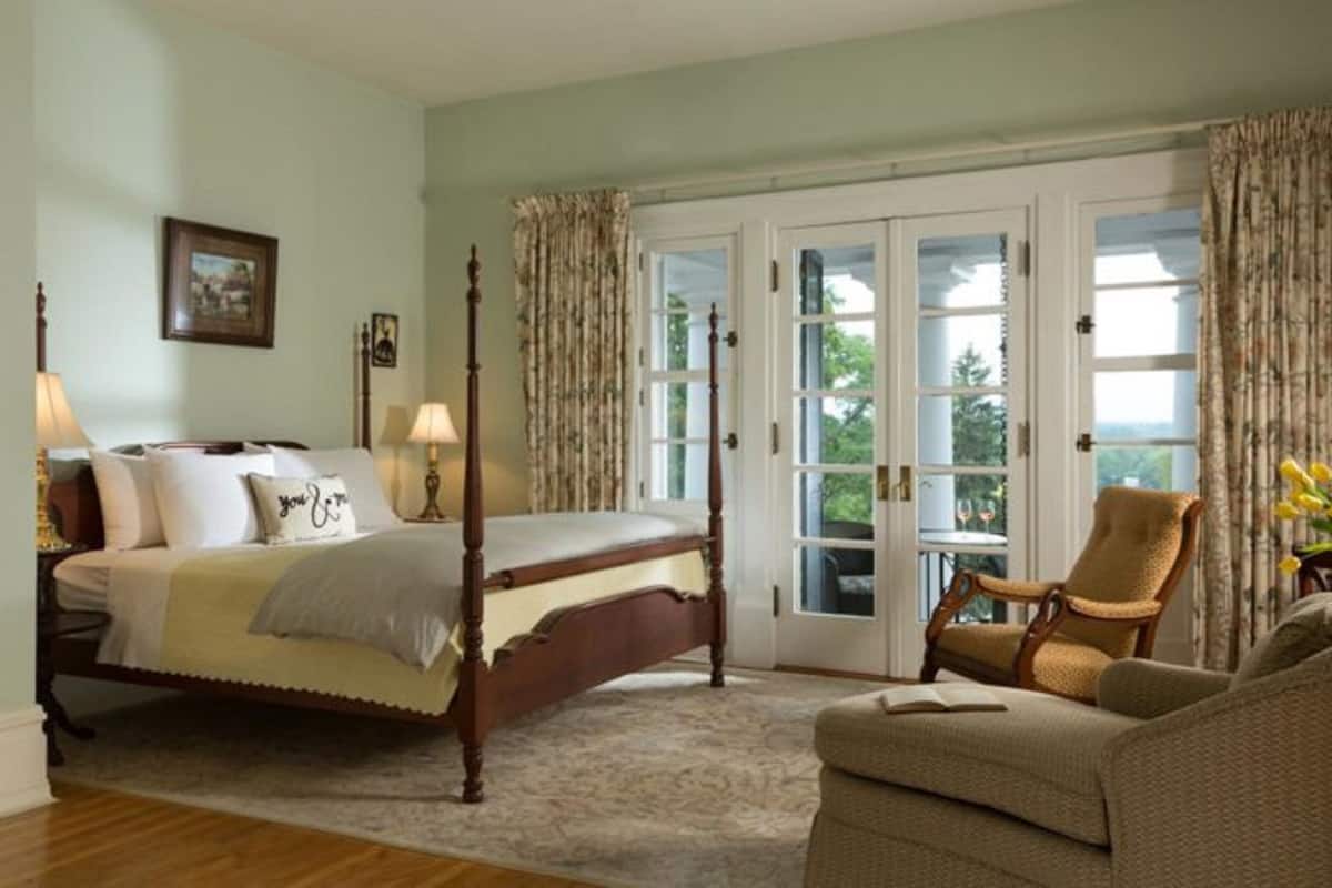 A bedroom with a four-poster bed, a chair, and a sofa.