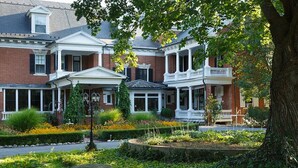 A row of brick townhouses with white trim, a covered porch, and a landscaped garden with a stone bench. - The Mercersburg Inn (Mercersburg)