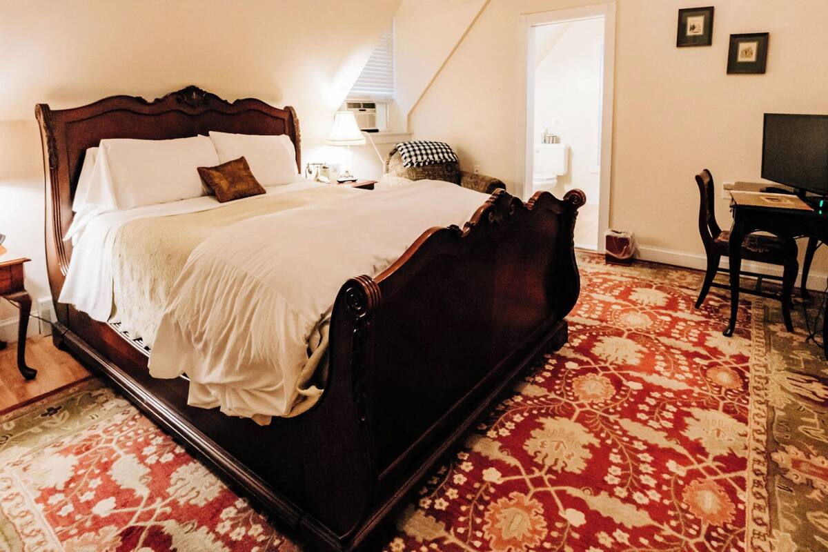 A bedroom with a large bed, a desk, and a chair.