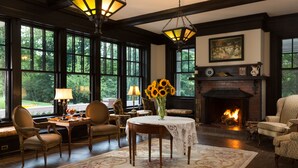 A cozy room with a fireplace, large windows, and a table with chairs. - The Mercersburg Inn (Mercersburg)
