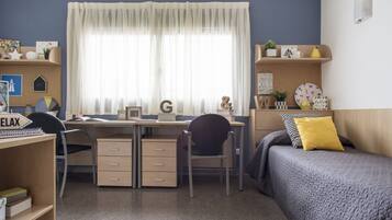 Un dormitorio ordenado con escritorio, silla y cama con almohada.