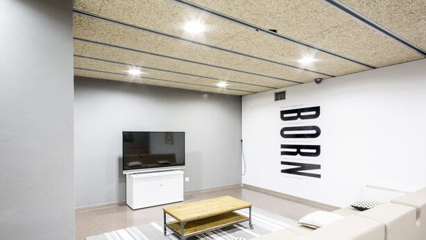 A modern living room with a flat-screen TV, a wooden coffee table, a white sofa, and a wall with the word "BORN" in large letters. - Residencia Universitaria Resa As Burgas - Centro Adscrito a REAJ - Campus Accomodation (Ourense)