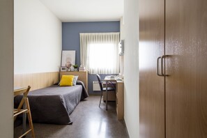 Une petite pièce comprenant un lit, un bureau et une chaise.