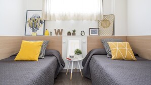 A hotel room with two beds, a small table with a plant, a framed picture, and a window with sheer curtains. - Residencia Universitaria Resa As Burgas - Centro Adscrito a REAJ - Campus Accomodation (Ourense)
