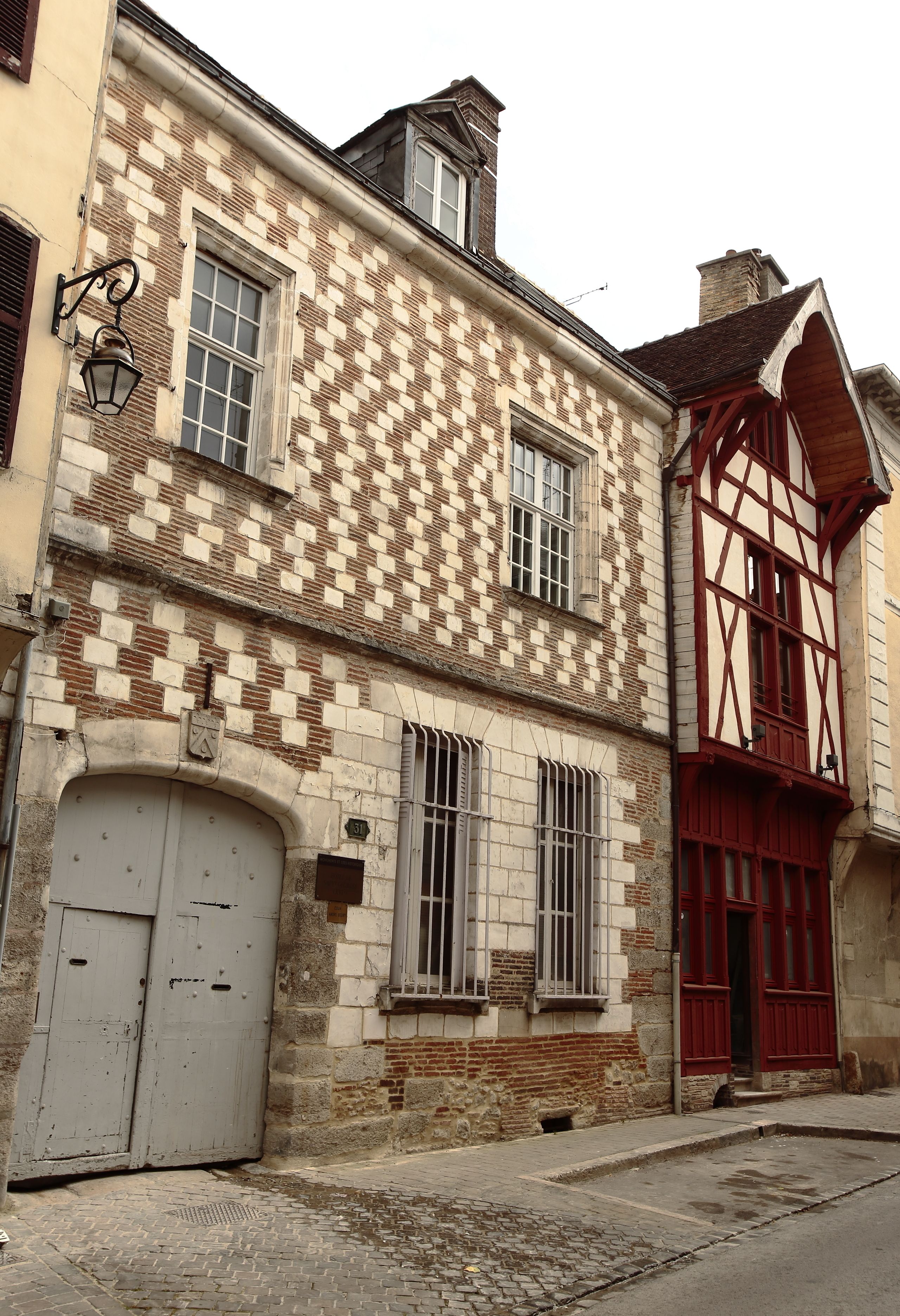 A historic building with a checkered facade, large windows, and a prominent red door.