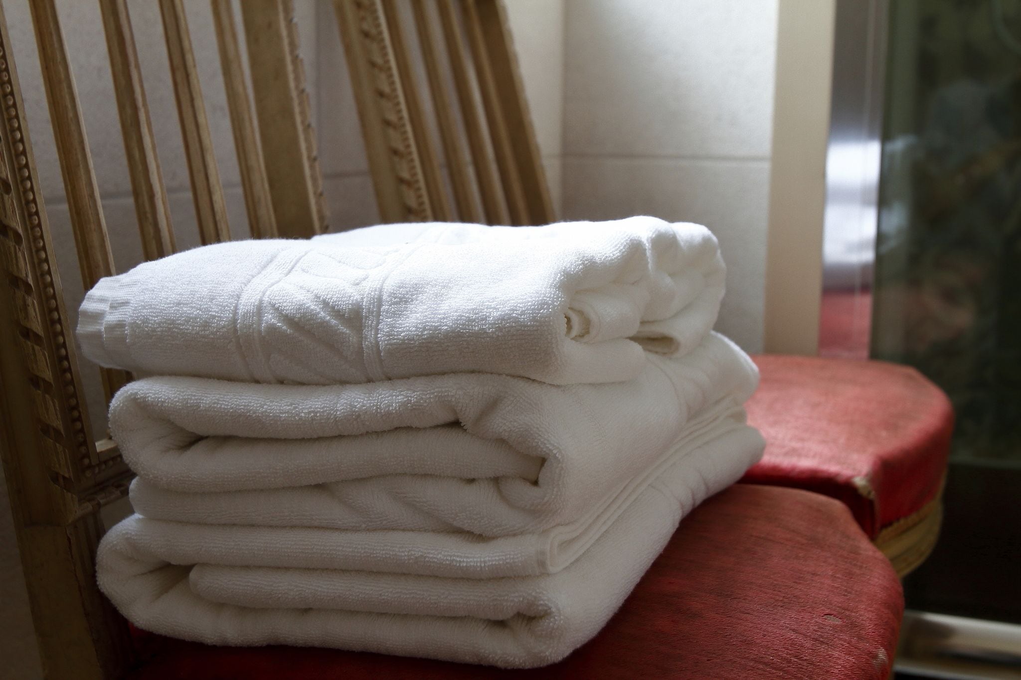 A stack of white towels on a red chair.