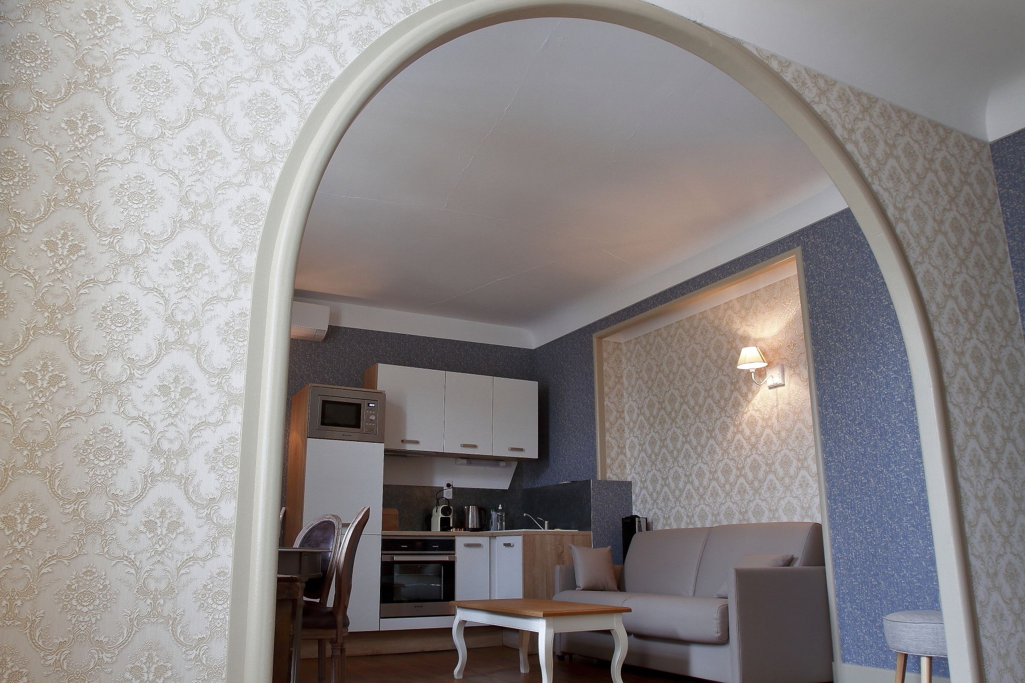 A compact living space with a kitchenette, a sofa, a dining table, and a mirror.
