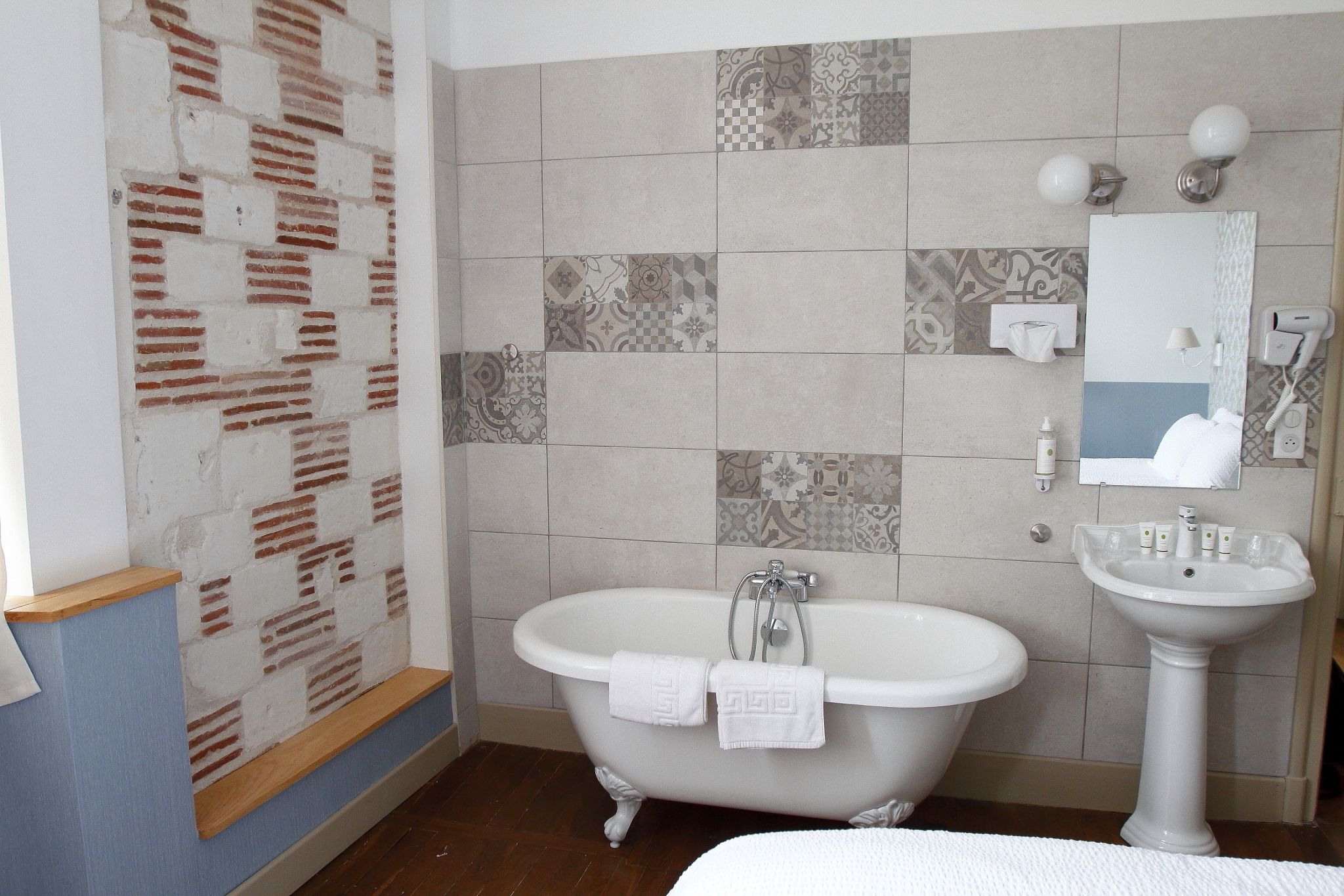 A bathroom with a freestanding bathtub, a pedestal sink, and a mirror above the sink.