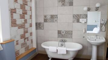 A bathroom with a freestanding bathtub, a pedestal sink, and a mirror above the sink.